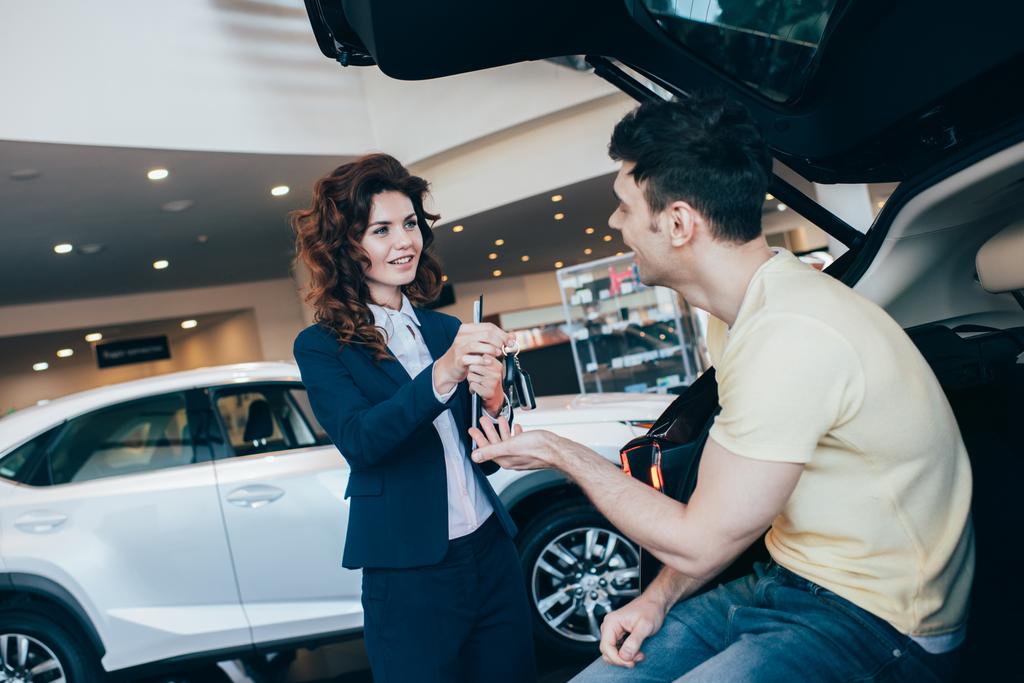 selective focus of happy customer taking car keys from attractive car dealer - Photo, Image