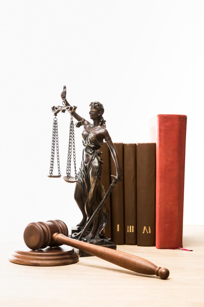 beeldje met schubben van Justitie, hamer en boeken over houten tafel geïsoleerd op wit - Foto, afbeelding