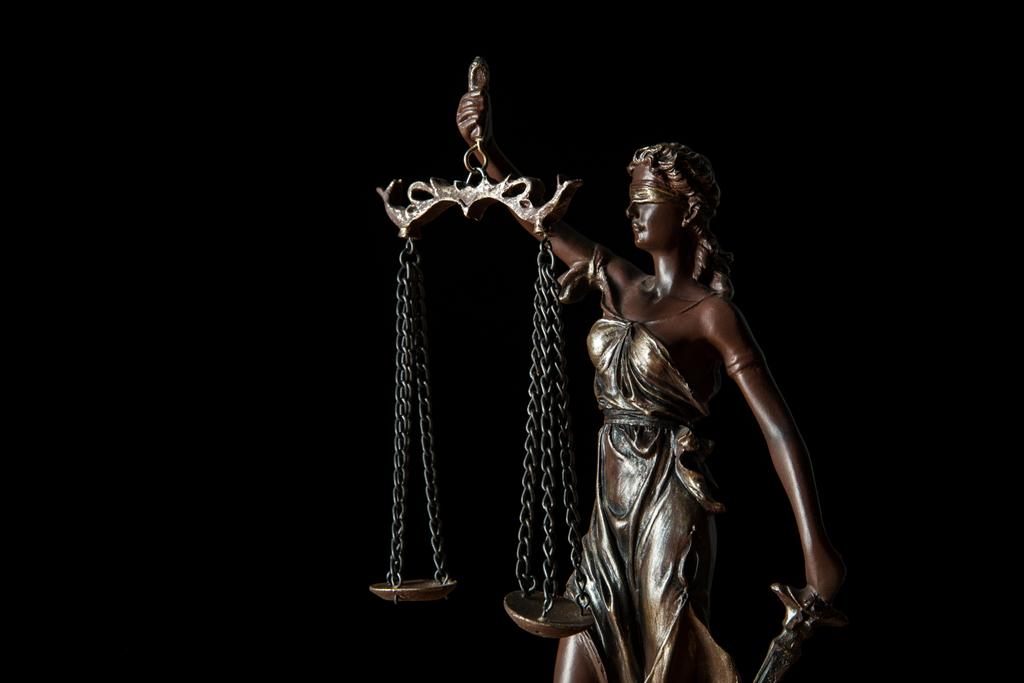 κοντινό πλάνο χάλκινο αγαλματίδιο με κλίμακες της δικαιοσύνης που απομονώνονται σε μαύρο - Φωτογραφία, εικόνα