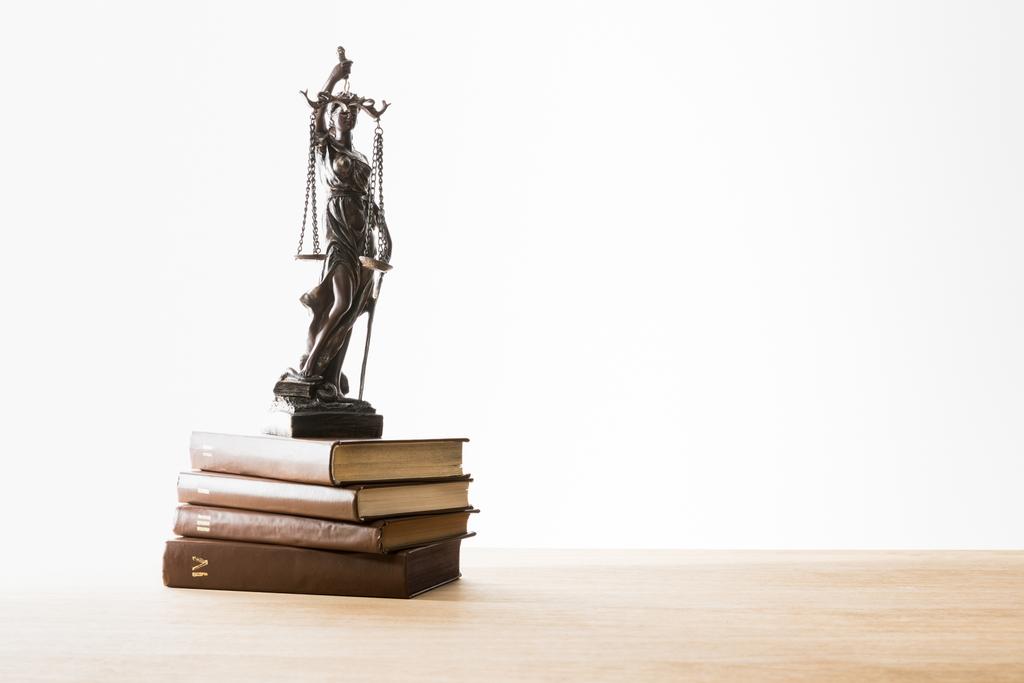 bronze figurine with scales of justice on brown books on wooden table isolated on white - Photo, Image