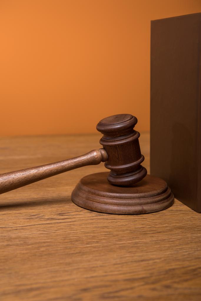close up of brown book in leather cover and gavel on wooden table isolated on orange - Photo, Image