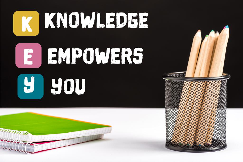 notebooks e lápis de cor na mesa com chave e conhecimento capacita você lettering em preto
   - Foto, Imagem