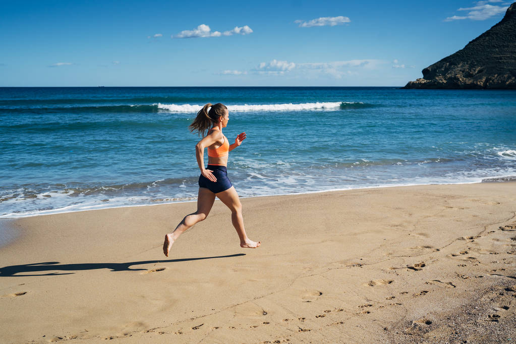 Fitness giovane donna che corre sulla spiaggia durante le vacanze estive
 - Foto, immagini