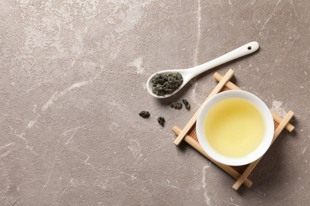 Чашка Tie Guan Yin oolong и ложка с чайными листьями на столе, вид сверху. Пространство для текста
 - Фото, изображение