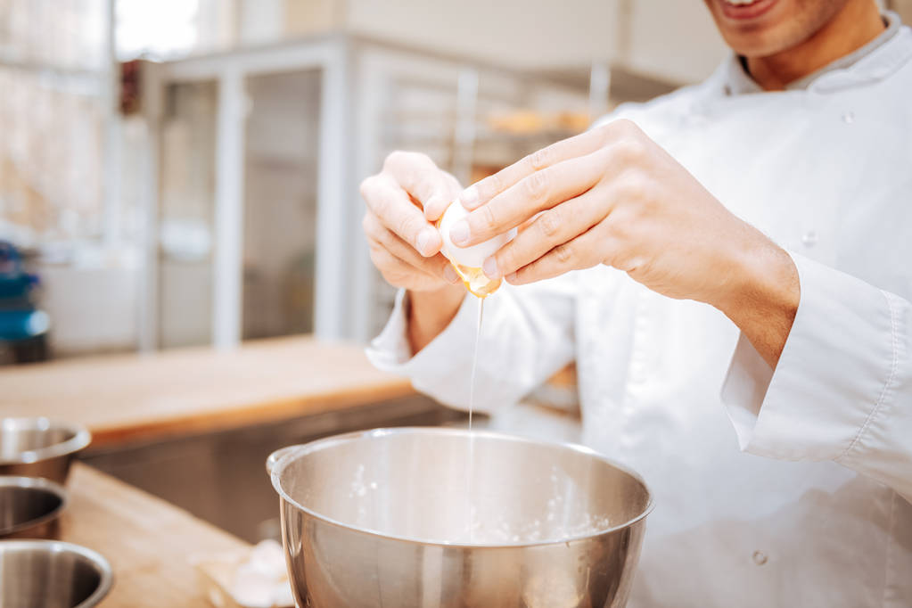 Baker portant une veste blanche battant l'oeuf pendant la cuisson de la pâtisserie
 - Photo, image