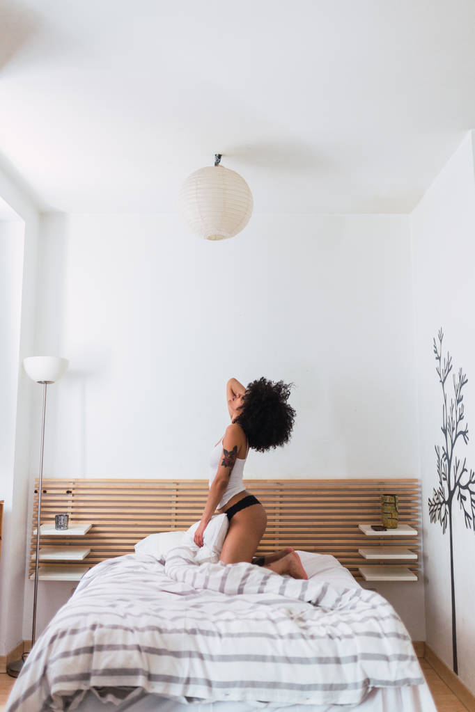 Jeune femme noire en lingerie posant sur le lit
 - Photo, image