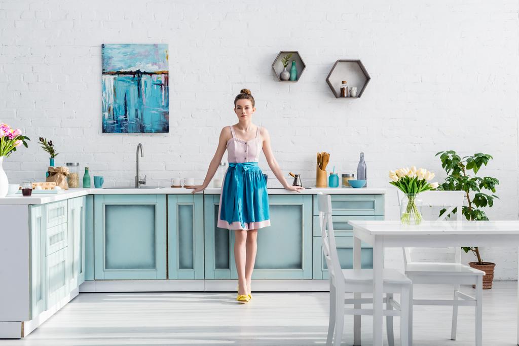 όμορφο κομψό νεαρή γυναίκα στην ποδιά στέκεται στην κουζίνα - Φωτογραφία, εικόνα