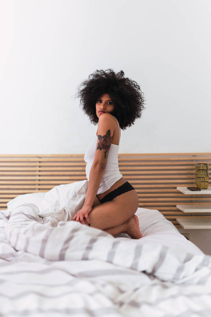 Jeune femme noire charmante en lingerie posant sur le lit
 - Photo, image