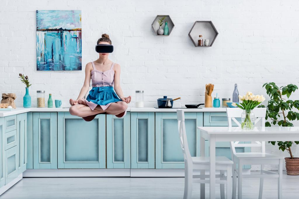 junge Frau schwebt in Lotus-Pose und Virtual-Reality-Headset in der Luft - Foto, Bild