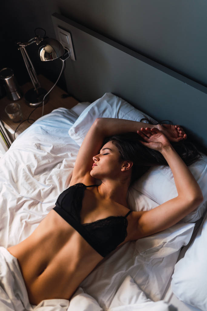 Jonge sensuele slanke vrouw in lingerie op bed slapen - Foto, afbeelding