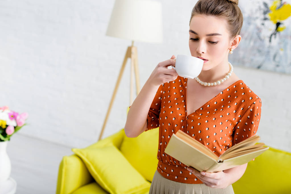 привлекательная элегантная молодая женщина в жемчужном ожерелье держит книгу и пьет кофе
 - Фото, изображение