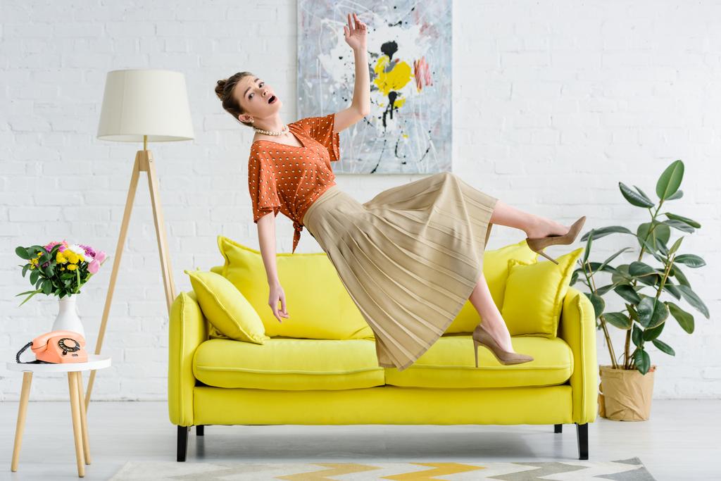 vista lateral de chocado elegante jovem levitar no ar na sala de estar
 - Foto, Imagem