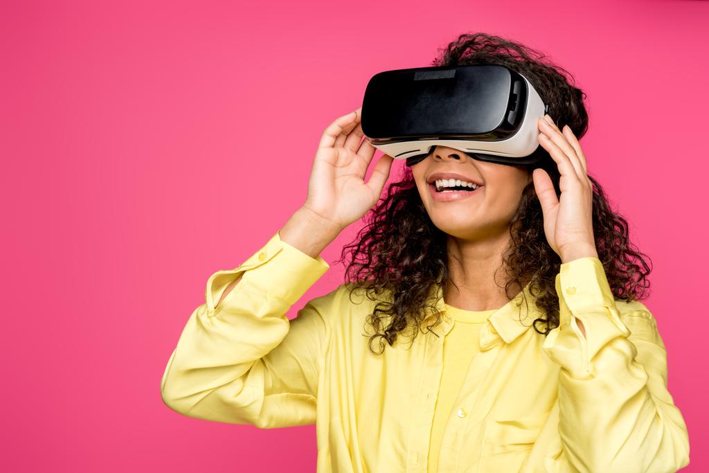 fröhliche afrikanisch-amerikanische Frau trägt Virtual-Reality-Headset isoliert auf Purpur  - Foto, Bild