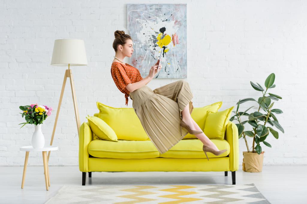 jovem elegante levitando no ar e usando tablet digital na sala de estar
 - Foto, Imagem