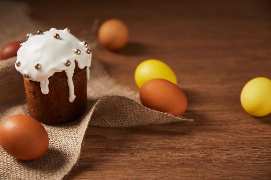 ζωγραφισμένα κοτόπουλο αυγά και το νόστιμο Πασχαλινό κέικ διακοσμημένο με ψεκάζει σε λινάτσα - Φωτογραφία, εικόνα