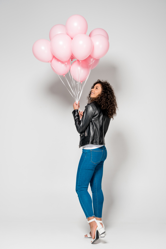 gri üzerinde pembe Hava balonlar bakarak neşeli Afrikalı Amerikan Genç kadın - Fotoğraf, Görsel