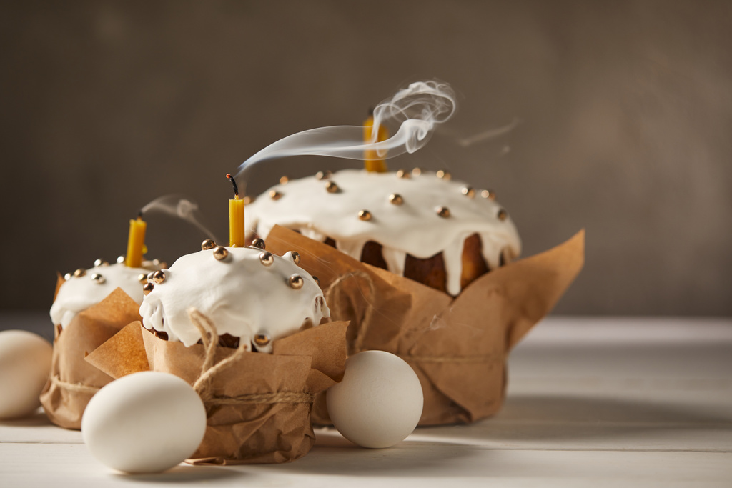 slepičí vejce a tradiční velikonoční dorty se svíčkami, sypání a polevu na bílém stole  - Fotografie, Obrázek