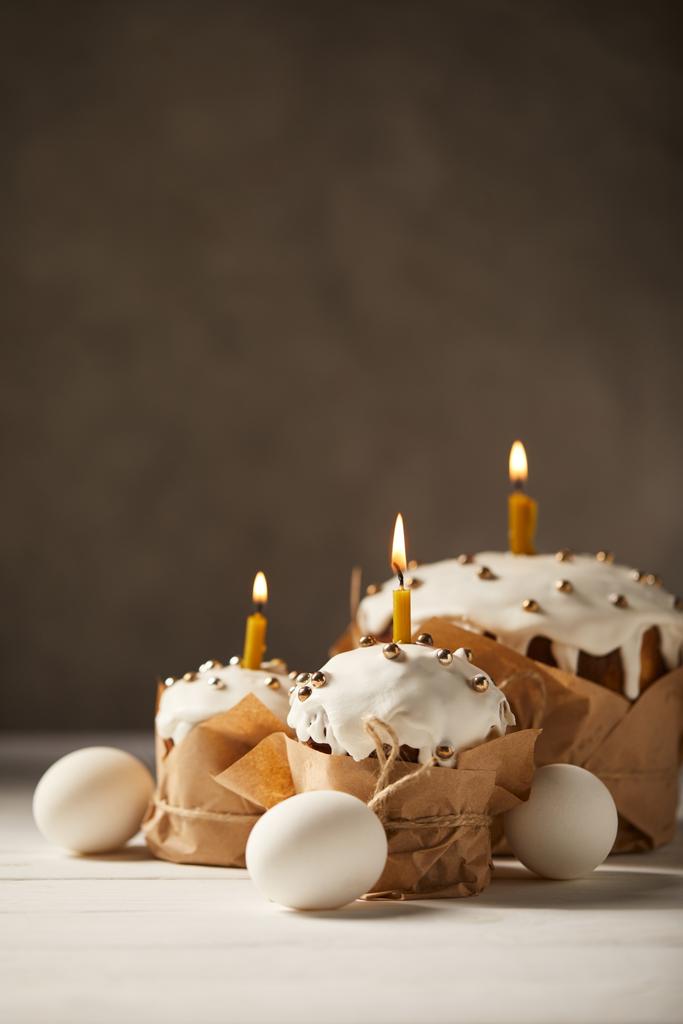 bolos de Páscoa tradicionais com velas em chamas e ovos de galinha na mesa branca
 - Foto, Imagem