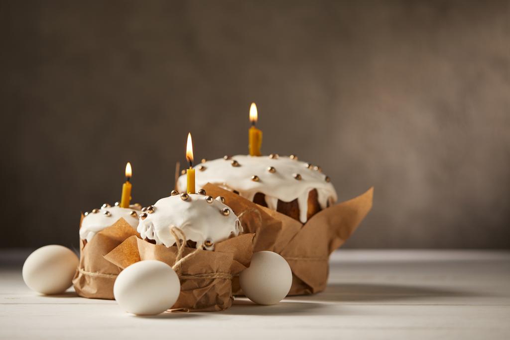 traditional easter cakes with burning candles and chicken eggs on white table with copy space - Photo, Image