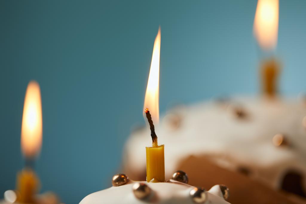 Zavřít o velikonoční dort zdobený sypání a hořící svíčku na tyrkysové - Fotografie, Obrázek