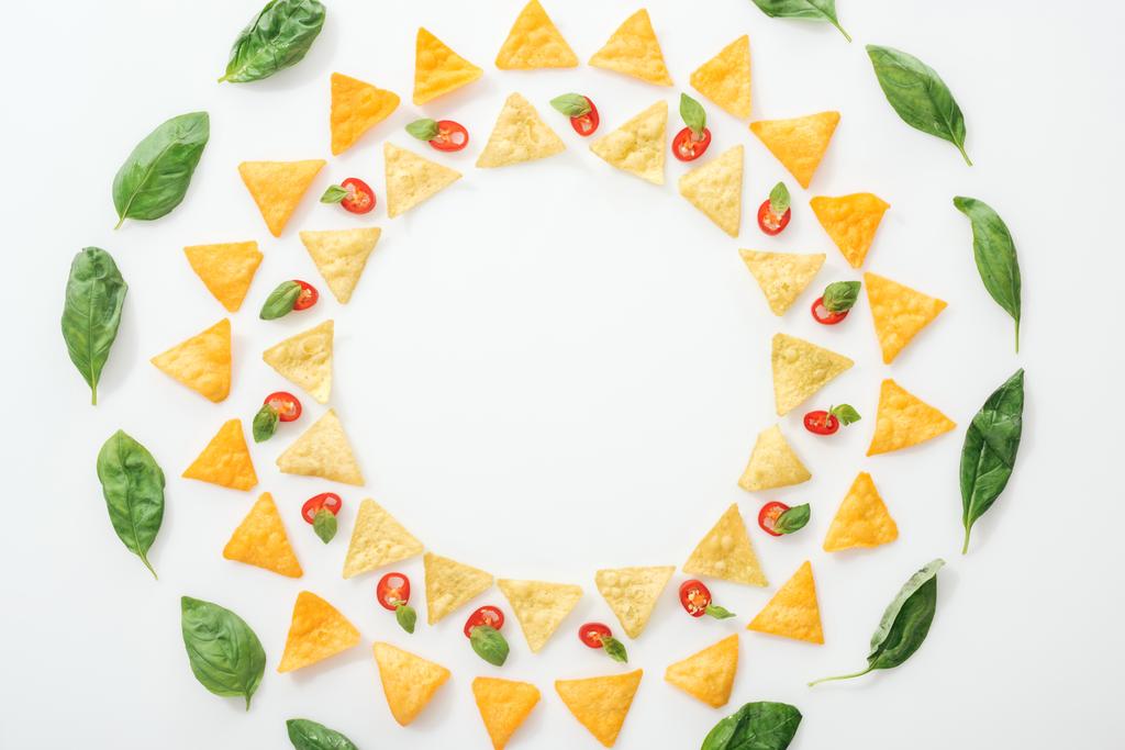 Nejlepší pohled na chutné nachos a plátky chilli papriček s bazalkou na bílém pozadí - Fotografie, Obrázek