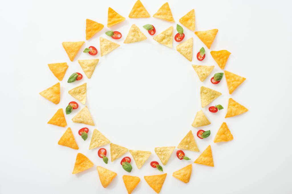 vista dall'alto di gustosi nachos e peperoncini affettati con basilico su sfondo bianco con spazio per copiare
 - Foto, immagini