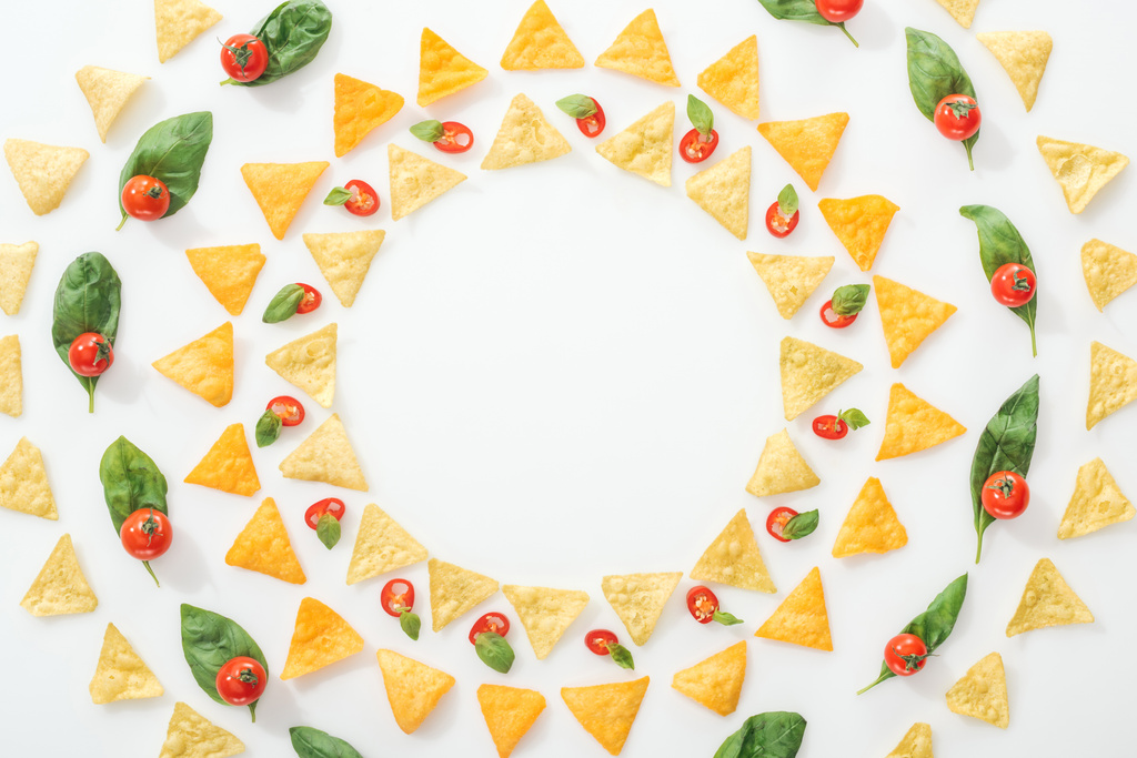 vista dall'alto di gustosi nachos e peperoncini tagliati con basilico e pomodorini
  - Foto, immagini