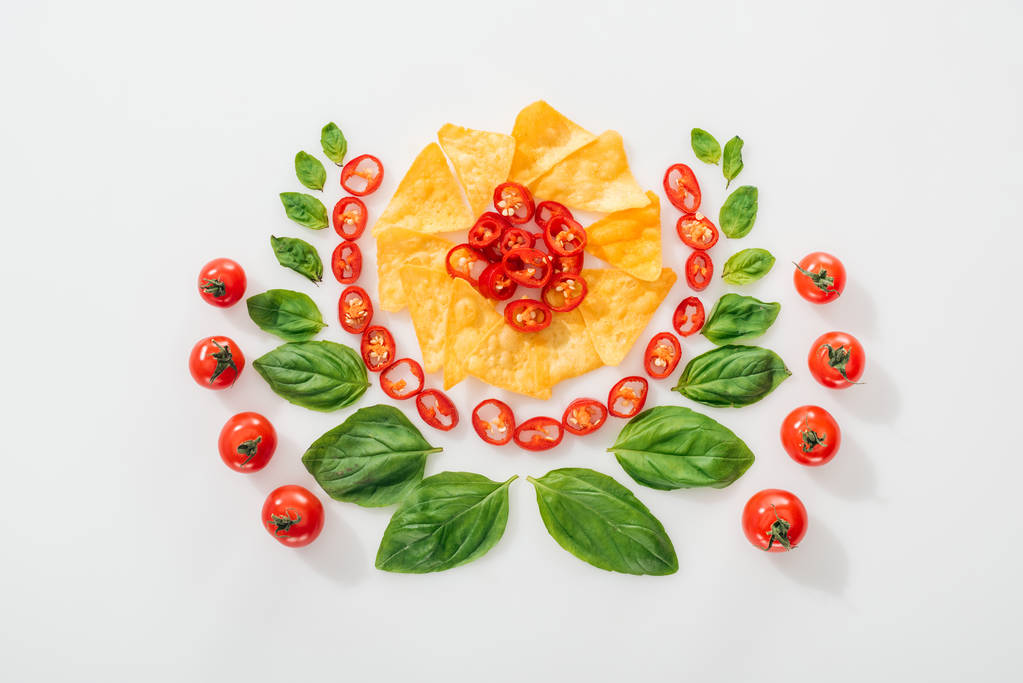 vista superior de nachos, pimentas cortadas, folhas de manjericão e tomates cereja maduros
  - Foto, Imagem