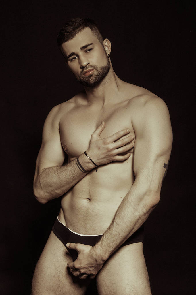 Músculo cara barbuda fuerte hermoso modelo masculino despojado en ropa interior negra sobre fondo de fuente aislado negro
 - Foto, Imagen