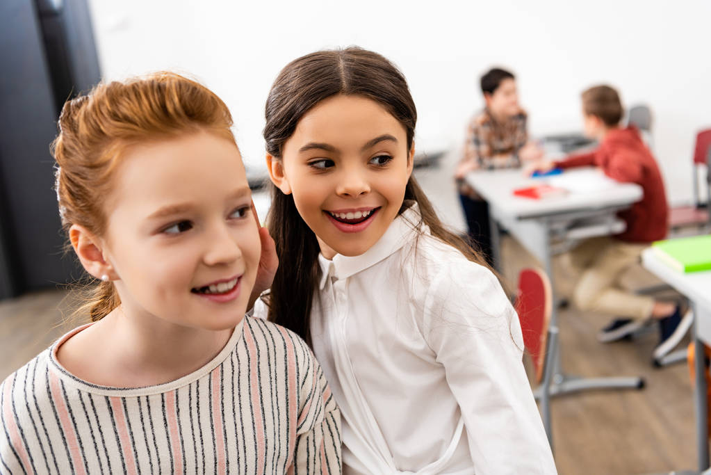 Dos colegialas lindas sonriendo y mirando hacia otro lado en el aula durante el freno
 - Foto, Imagen