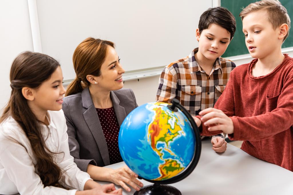 教室で地理を勉強しているときに地球を見ている教師と生徒 - 写真・画像