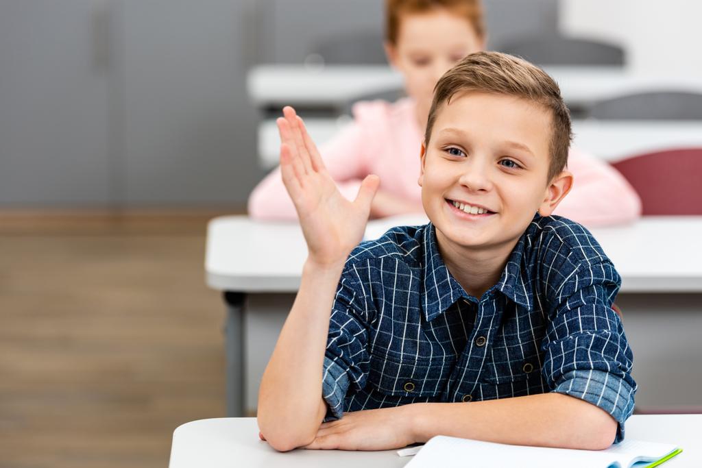 Schoolboy w Checkered shirt podnoszenie ręka w górę podczas Lekcja w Klasa - Zdjęcie, obraz