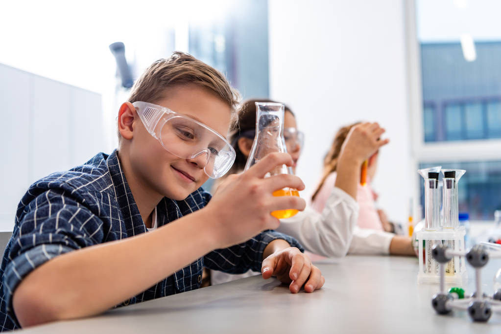 Schüler mit Schutzbrille halten im Chemieunterricht Becher in der Hand - Foto, Bild