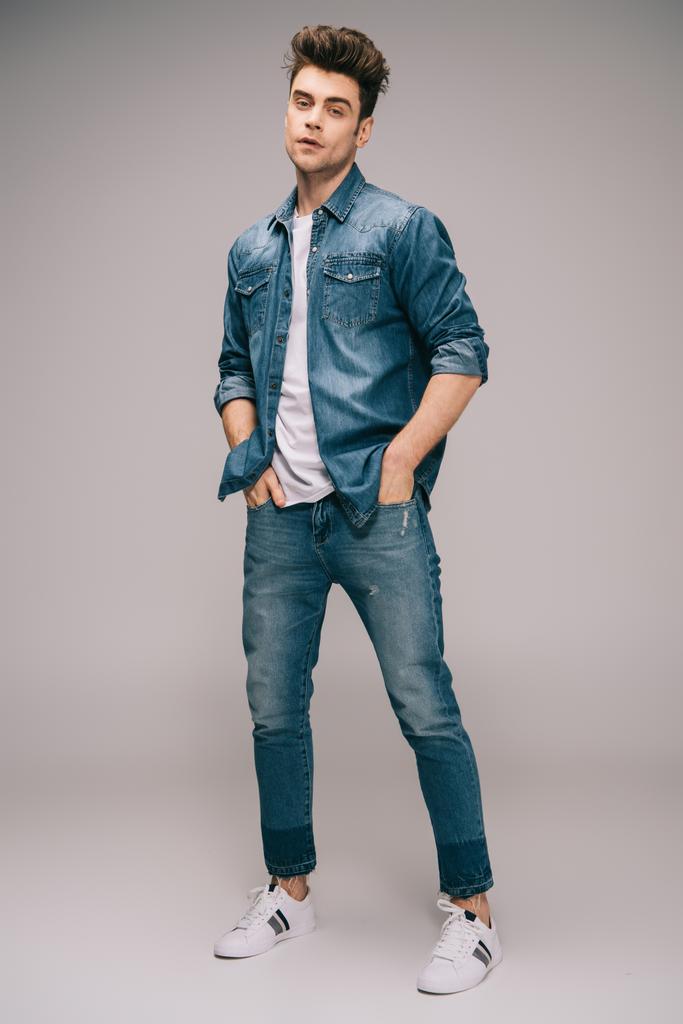 hombre guapo y guapo en jeans, falda y camiseta con las manos en los bolsillos mirando a la cámara
  - Foto, Imagen
