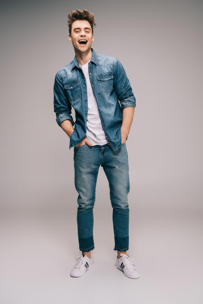 smiling and good-looking man in jeans, skirt and t-shirt with hands in pockets looking at camera  - Photo, Image