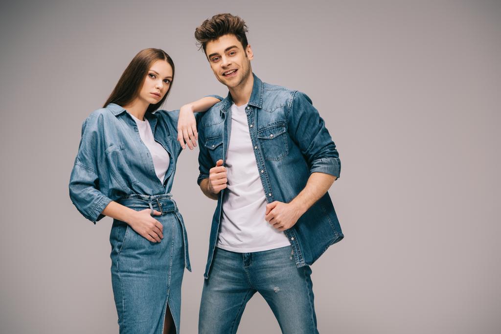 girlfriend in denim dress and smiling boyfriend in jeans and shirt looking at camera  - Photo, Image
