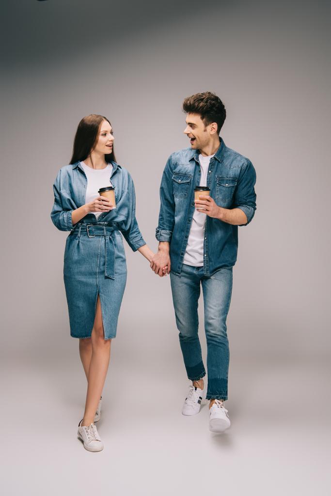 девушка в джинсовом платье и симпатичный парень в джинсах и рубашке держа бумажные стаканчики и держась за руки
  - Фото, изображение