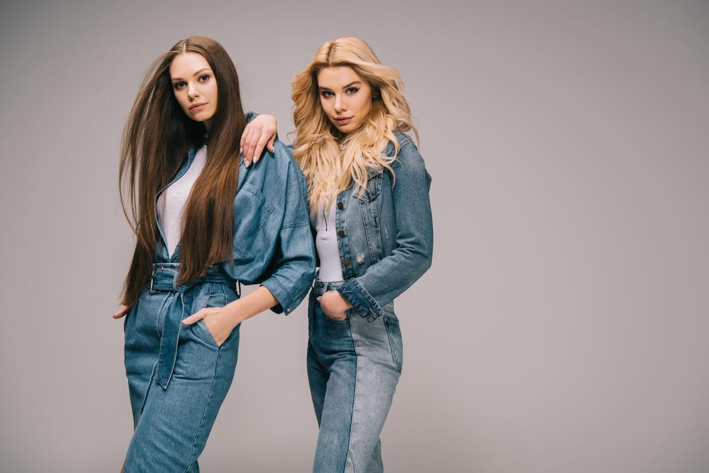 blonde and brunette women in denim clothes with hands in pockets looking at camera  - Photo, Image