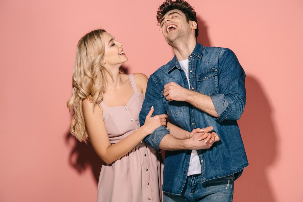 namorada sorridente em vestido rosa e namorado bonito na camisa jeans de mãos dadas
  - Foto, Imagem