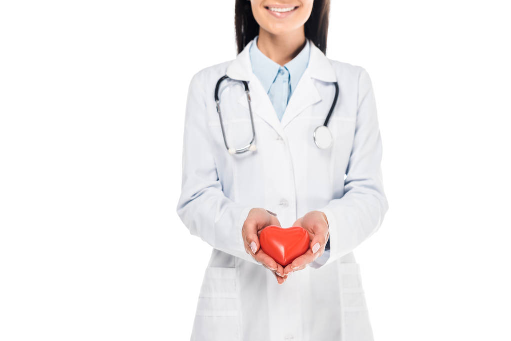 Częściowy widok lekarza w biały płaszcz gospodarstwa z tworzywa sztucznego serca na białym tle - Zdjęcie, obraz