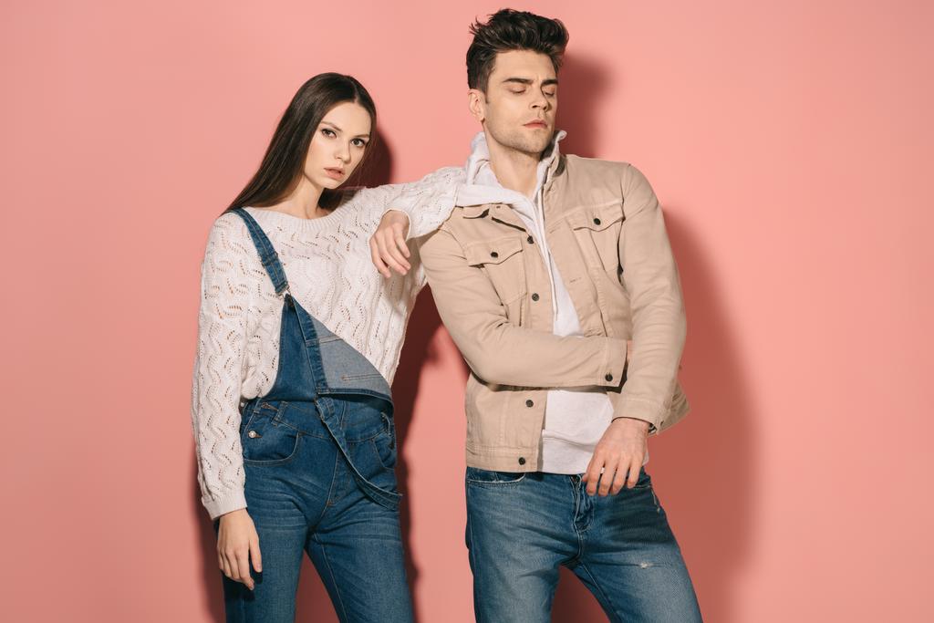 brünett und schöne Freundin in Jeans-Overalls und schöner Freund auf rosa Hintergrund  - Foto, Bild
