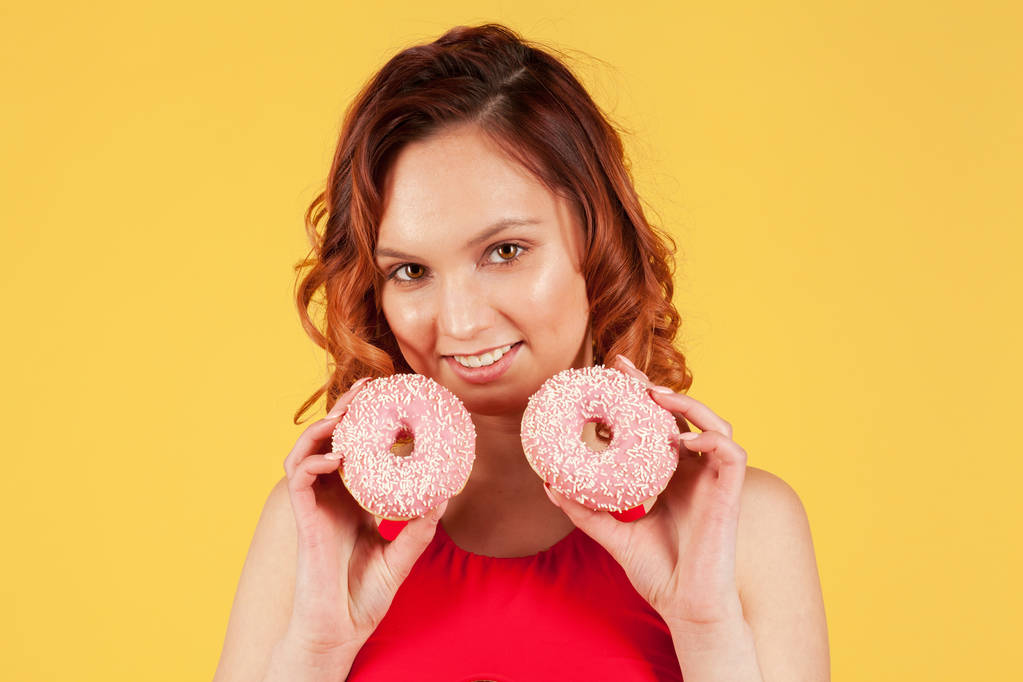 roze donuts in de handen van meisje op gele achtergrond - Foto, afbeelding