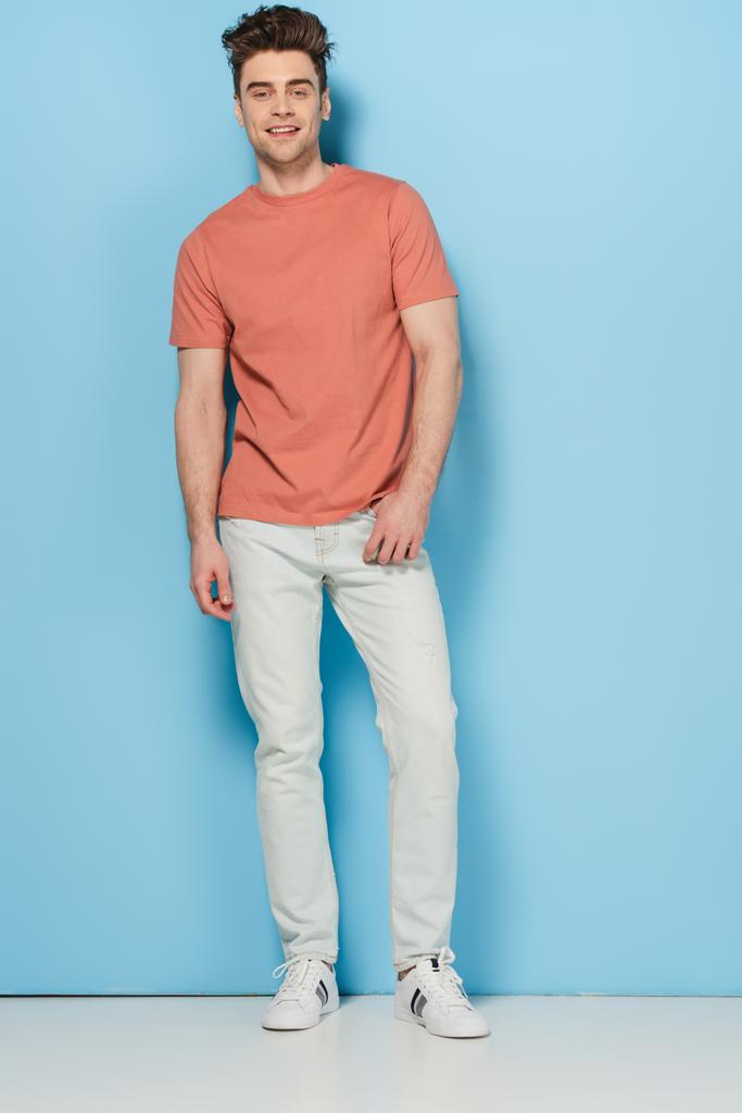handsome and brunette man in t-shirt and jeans looking at camera  - Photo, Image