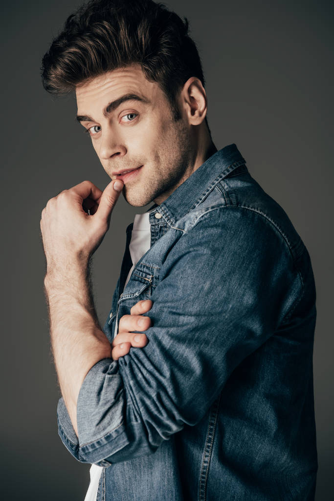 handsome and brunette man in denim shirt looking at camera isolated on black - Photo, Image