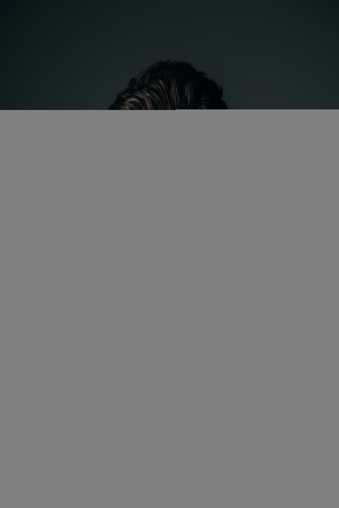 guapo y moreno hombre en camisa de mezclilla mirando a la cámara aislado en negro
 - Foto, Imagen