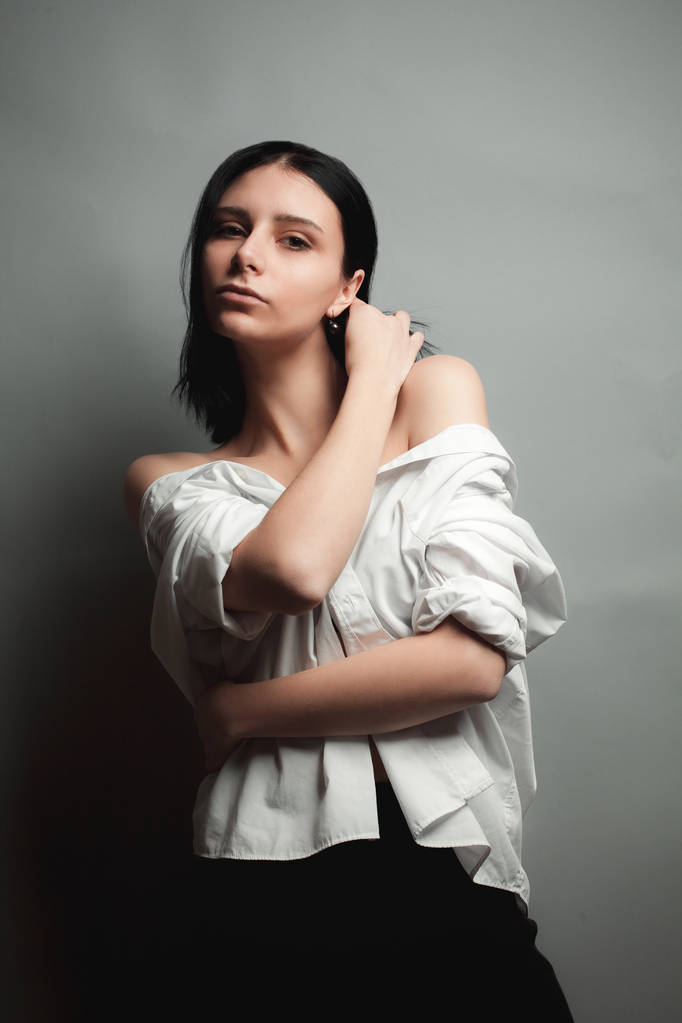 attraktive junge Frau im weißen Hemd mit nackten Schultern. Studio - Foto, Bild