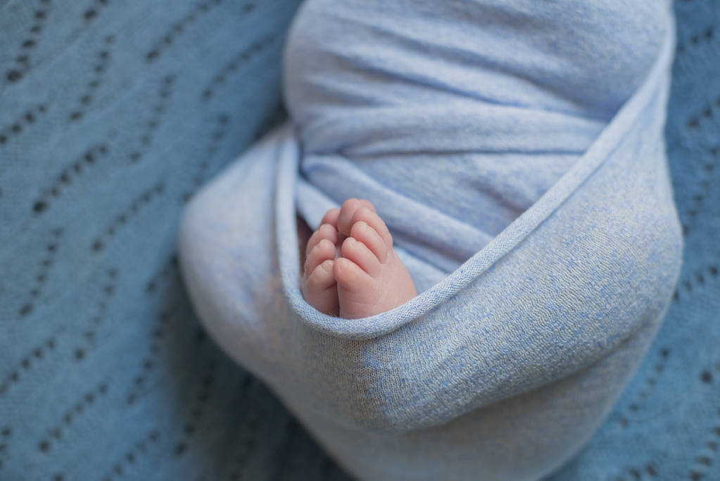pequenas pernas de bebê em cobertor azul na cama em casa
 - Foto, Imagem