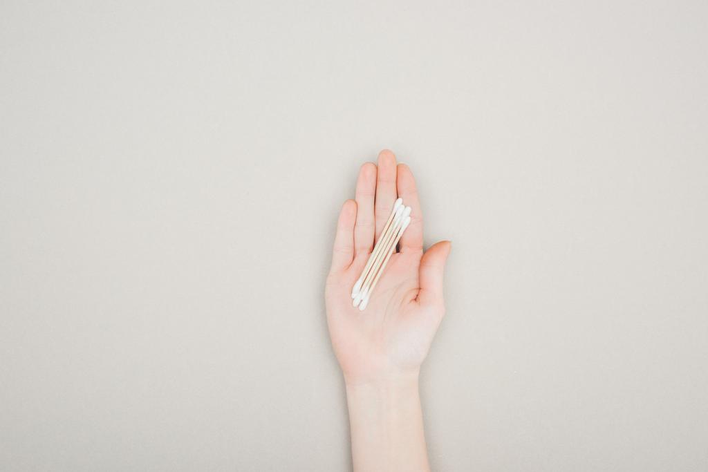 cropped view of woman holding cotton swabs on grey background - Photo, Image