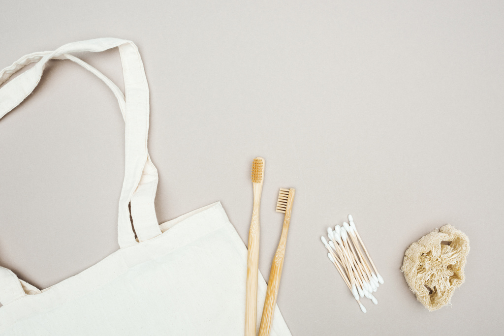 escovas de dentes de madeira, loofah orgânico, cotonetes e saco de algodão branco sobre fundo cinza
 - Foto, Imagem