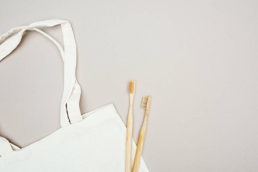 wooden toothbrushes and white cotton bag on grey background - Photo, Image